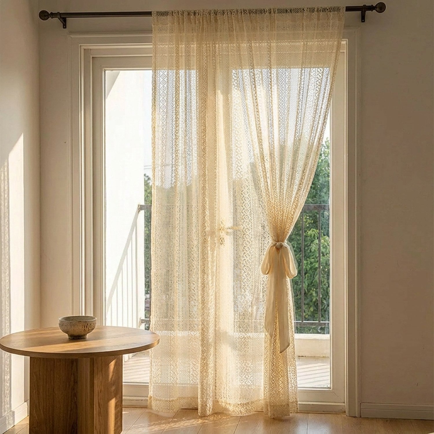 Voilage beige noué près d'une porte fenêtre donnant sur un balcon verdoyant