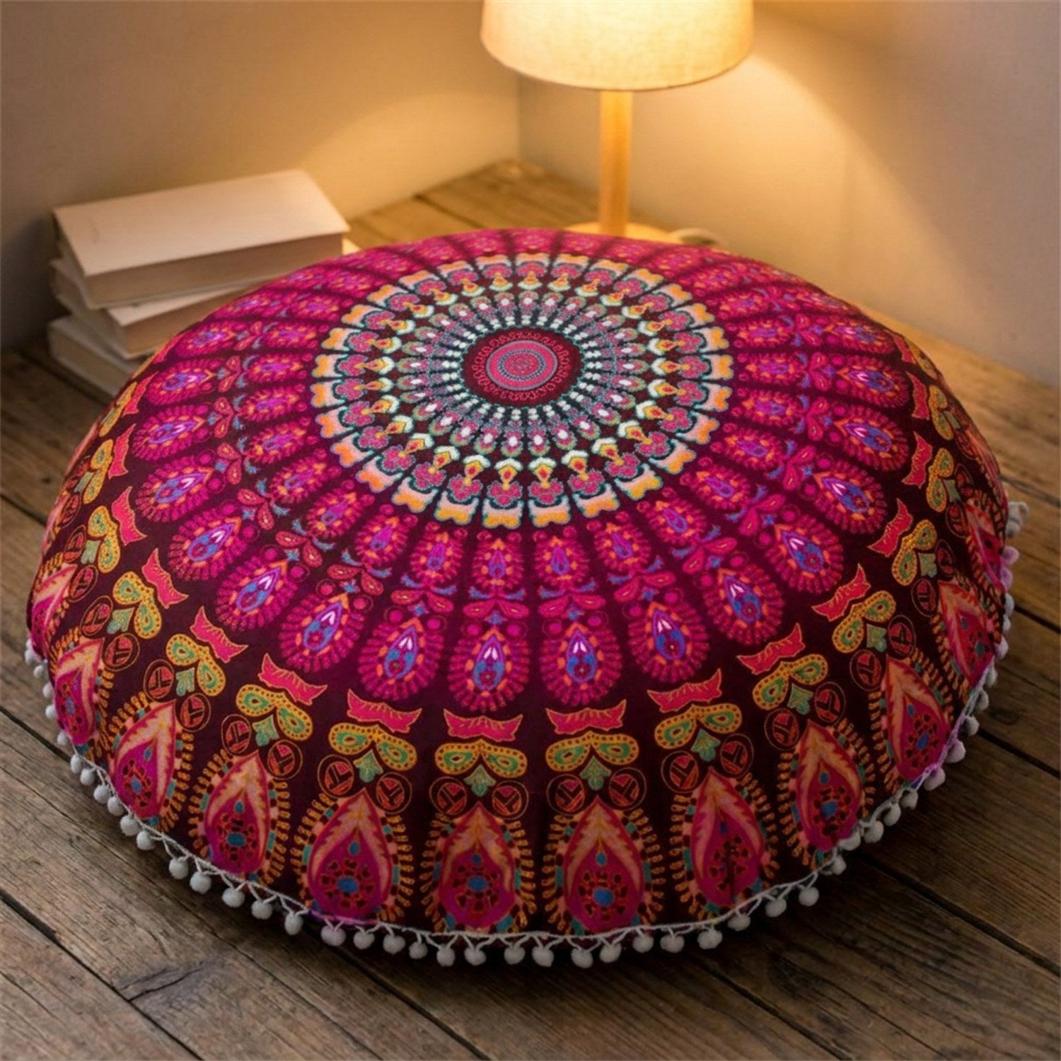 Housse de coussin mandala bordeaux posée au sol dans un coin lecture chaleureux le soir