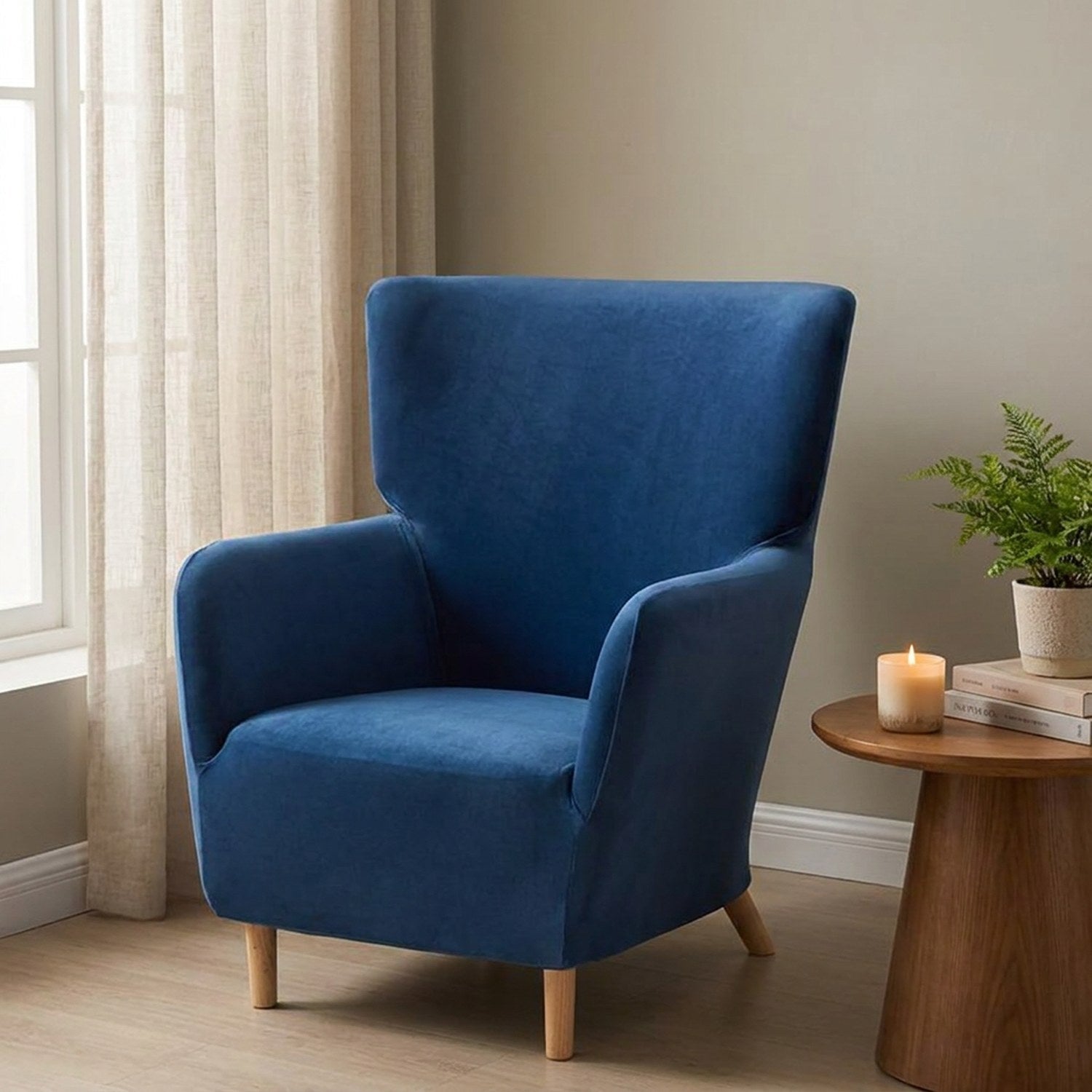 Fauteuil à oreilles en velours bleu près d'une fenêtre voilée dans un salon élégant