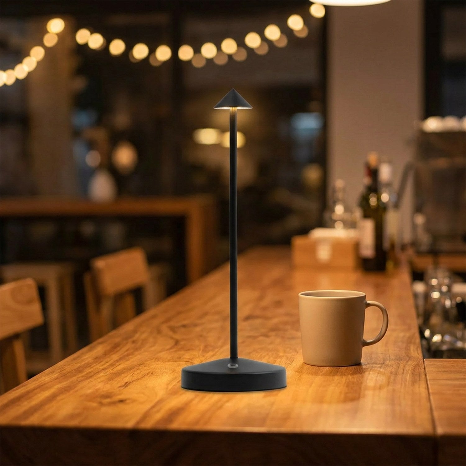 Lampe de table noire allumée sur un comptoir de café le soir