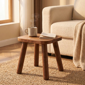 Tabouret en bois massif comme bout de canapé avec une tasse et un livre