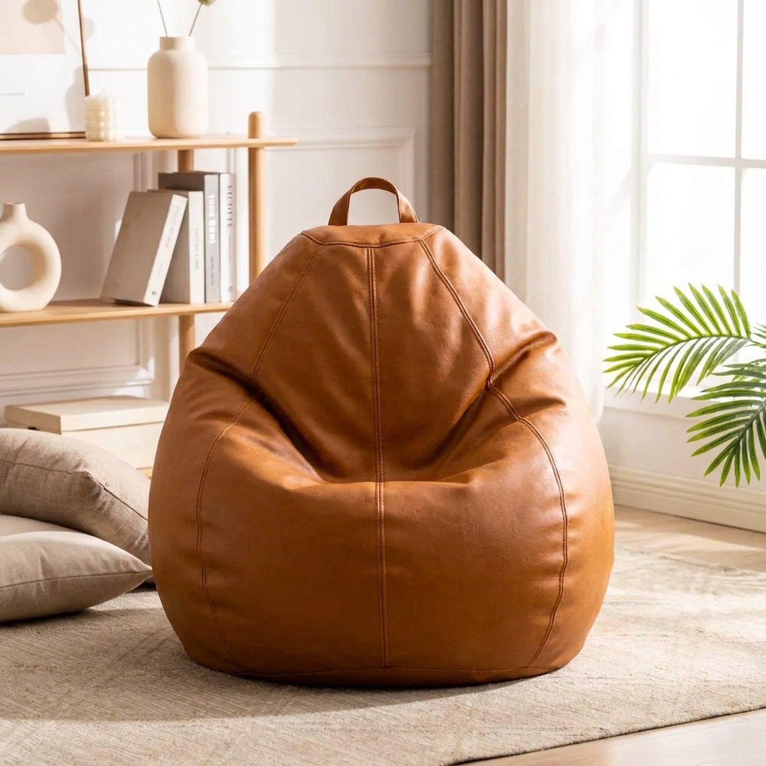 Pouf poire en simili cuir dans un coin détente lumineux avec coussins et plante
