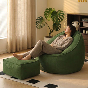 Personne allongée dans le fauteuil pouf vert les pieds sur le repose-pieds