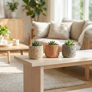 Trois cache-pots en ciment beige terracotta et gris alignés sur une console en bois