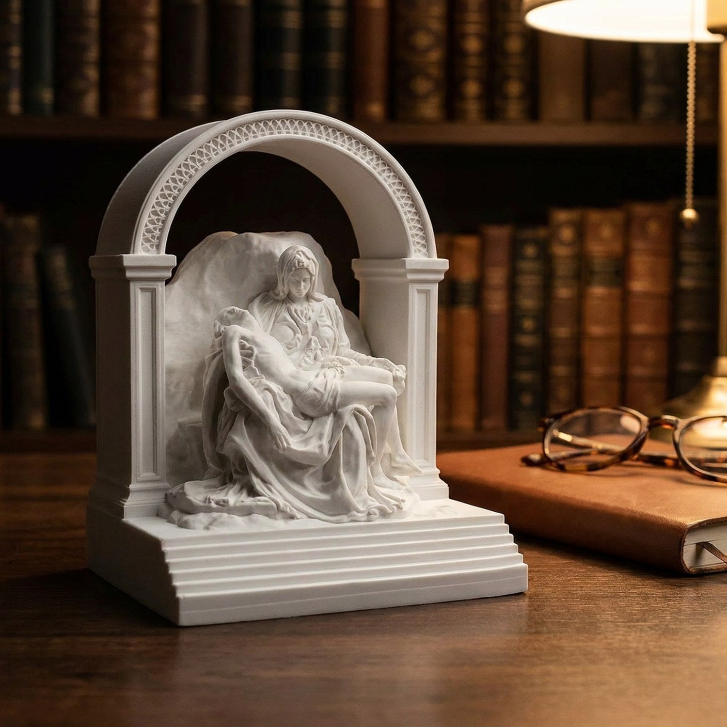 Statue de La Pietà sur un bureau d'étude près de lunettes et d'un carnet