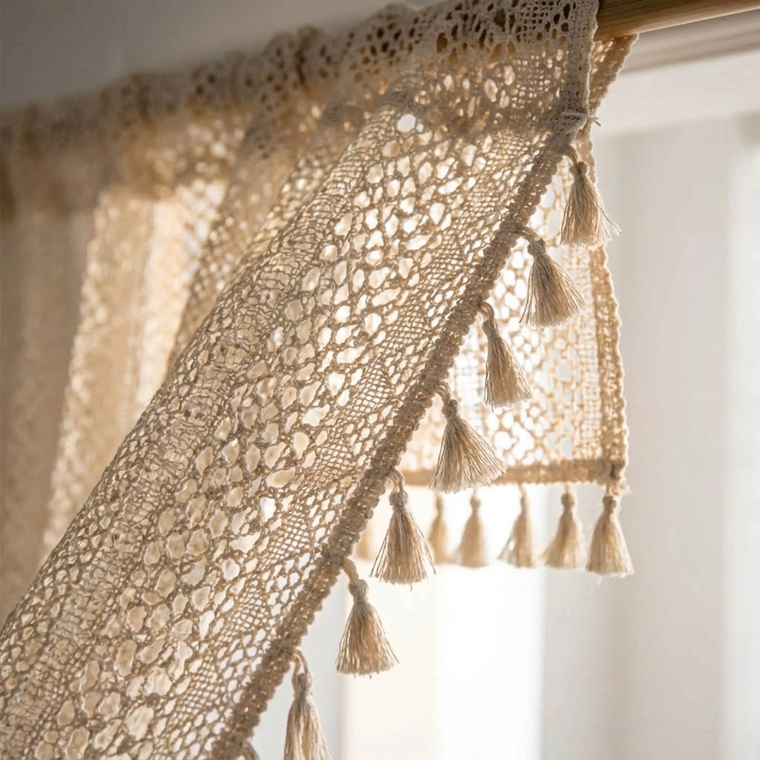 Détail de la dentelle au crochet et des pompons d'un rideau boho beige