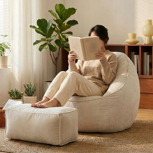 Personne assise dans le fauteuil pouf blanc les pieds sur le repose-pieds assorti