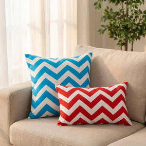 Coussins à chevrons bleus et rouges sur un canapé en lin dans un salon lumineux