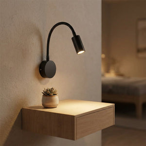 Applique murale liseuse noire au-dessus d'une table de chevet suspendue avec une plante