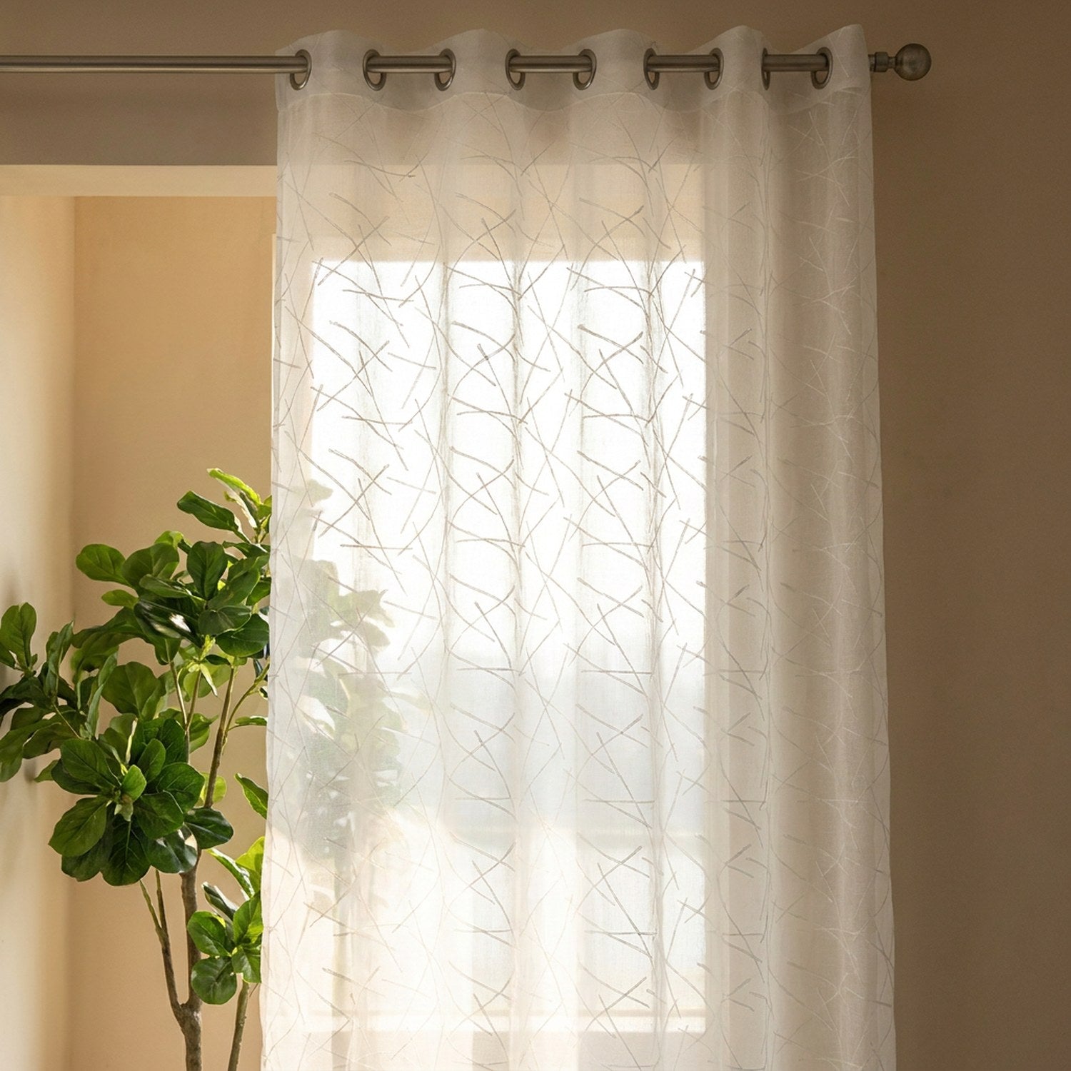 Gros plan sur le motif géométrique brodé du voilage blanc translucide à contre-jour