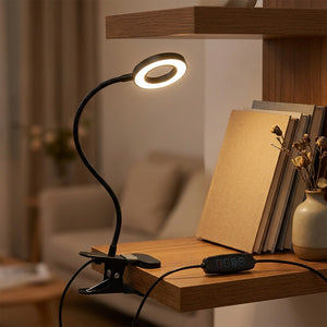 Lampe pince clipsée sur une étagère en bois au-dessus d'une pile de livres