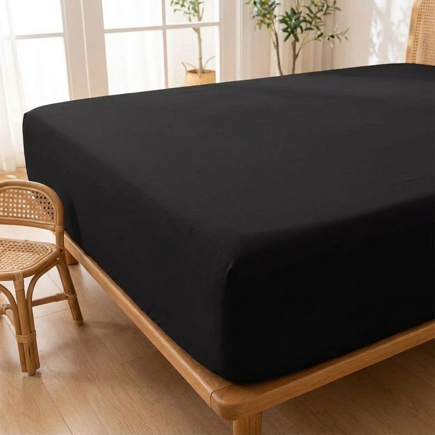Coin du drap housse noir tendu sur un lit près d'une fenêtre lumineuse