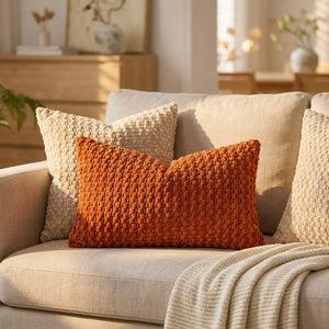housse de coussin en maille texturée terracotta sur un canapé en lin avec plaid