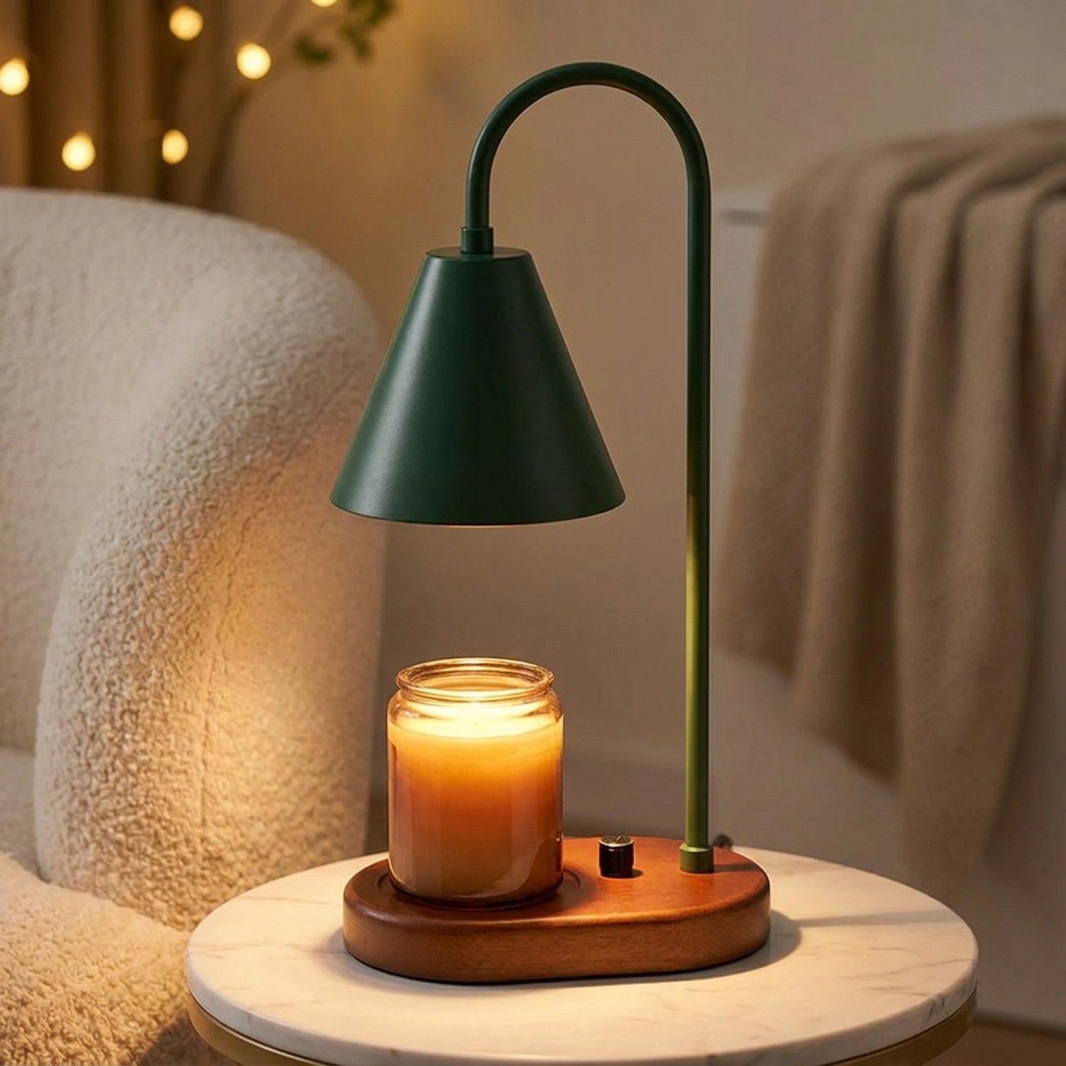 Lampe chauffe-bougie verte avec socle en bois sur une table d'appoint en marbre