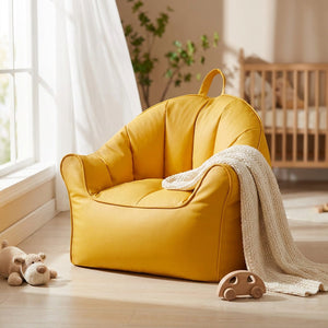 Pouf fauteuil enfant jaune près d'une fenêtre avec un plaid et des jouets en bois