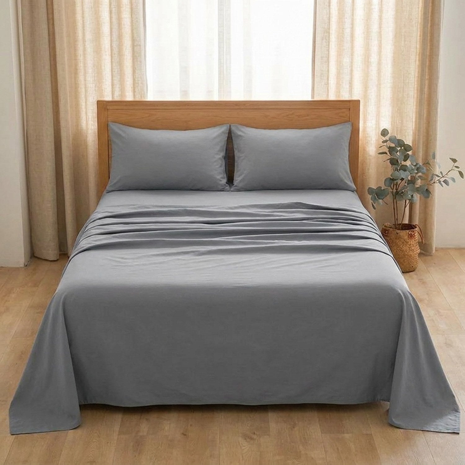 Drap plat gris sur un lit près d'une fenêtre avec rideaux en lin et plante d'eucalyptus