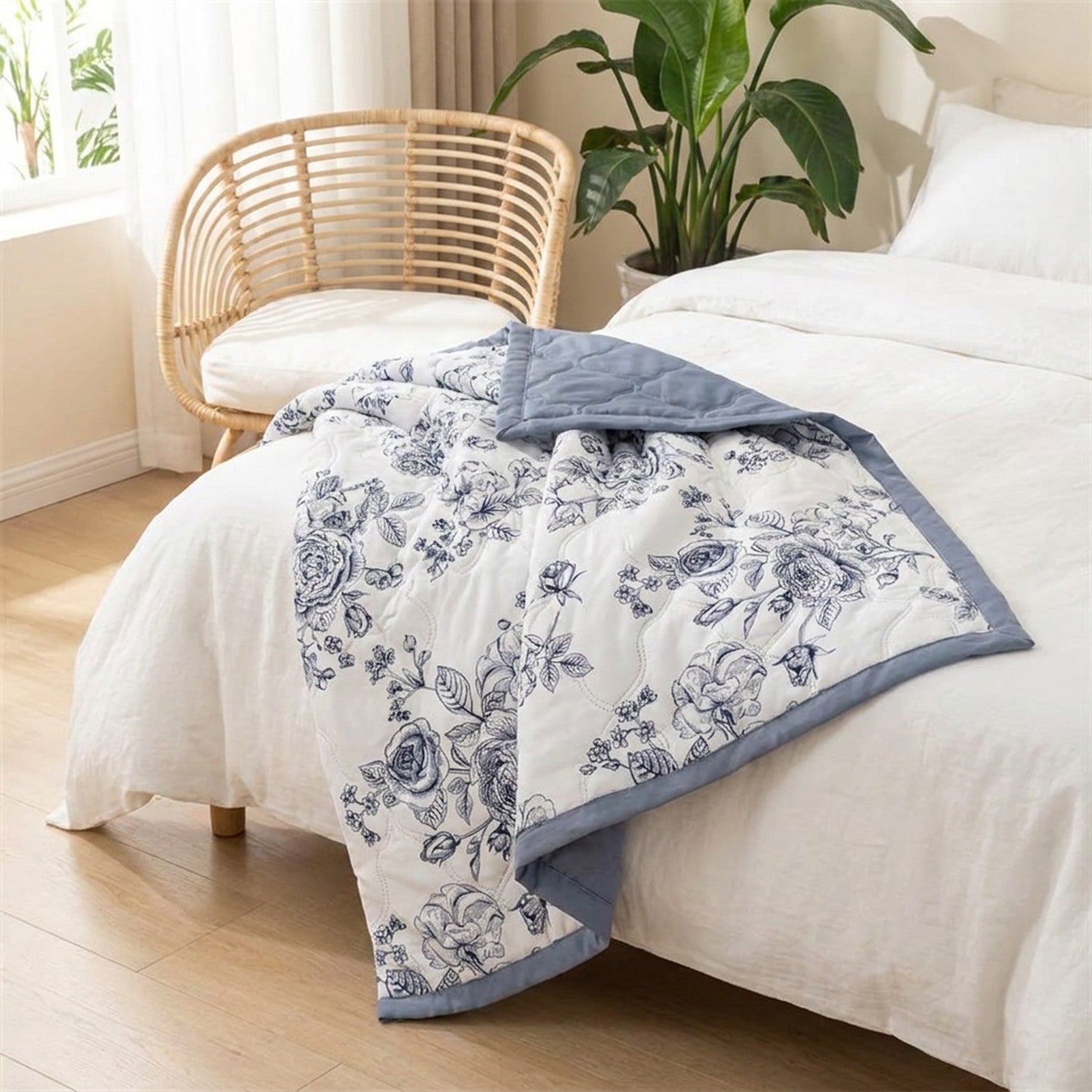 Couvre-lit matelassé d'été drapé sur un lit dans une chambre scandinave avec fauteuil en rotin