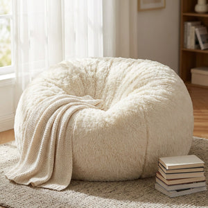 Pouf géant en fausse fourrure blanche dans un coin lecture avec plaid et livres