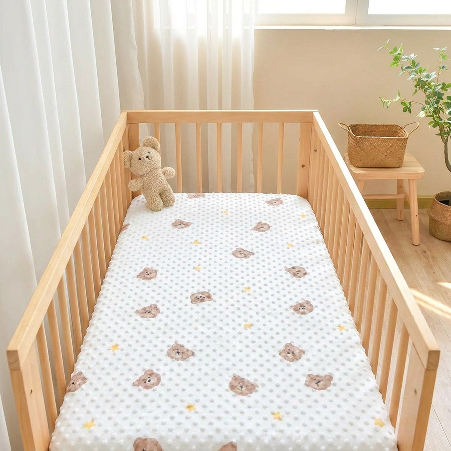 Berceau en bois habillé du drap-housse à pois dans une chambre lumineuse