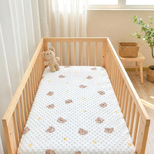 Berceau en bois habillé du drap-housse à pois dans une chambre lumineuse