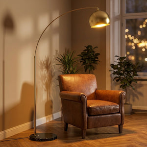 Lampadaire arc doré dans bureau cosy avec fauteuil cuir et bokeh