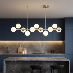 Lustre doré suspendu au dessus d'un îlot de cuisine avec tabourets noirs