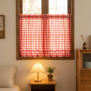 Rideau à carreaux rouges suspendu à une fenêtre de chambre avec lampe de chevet