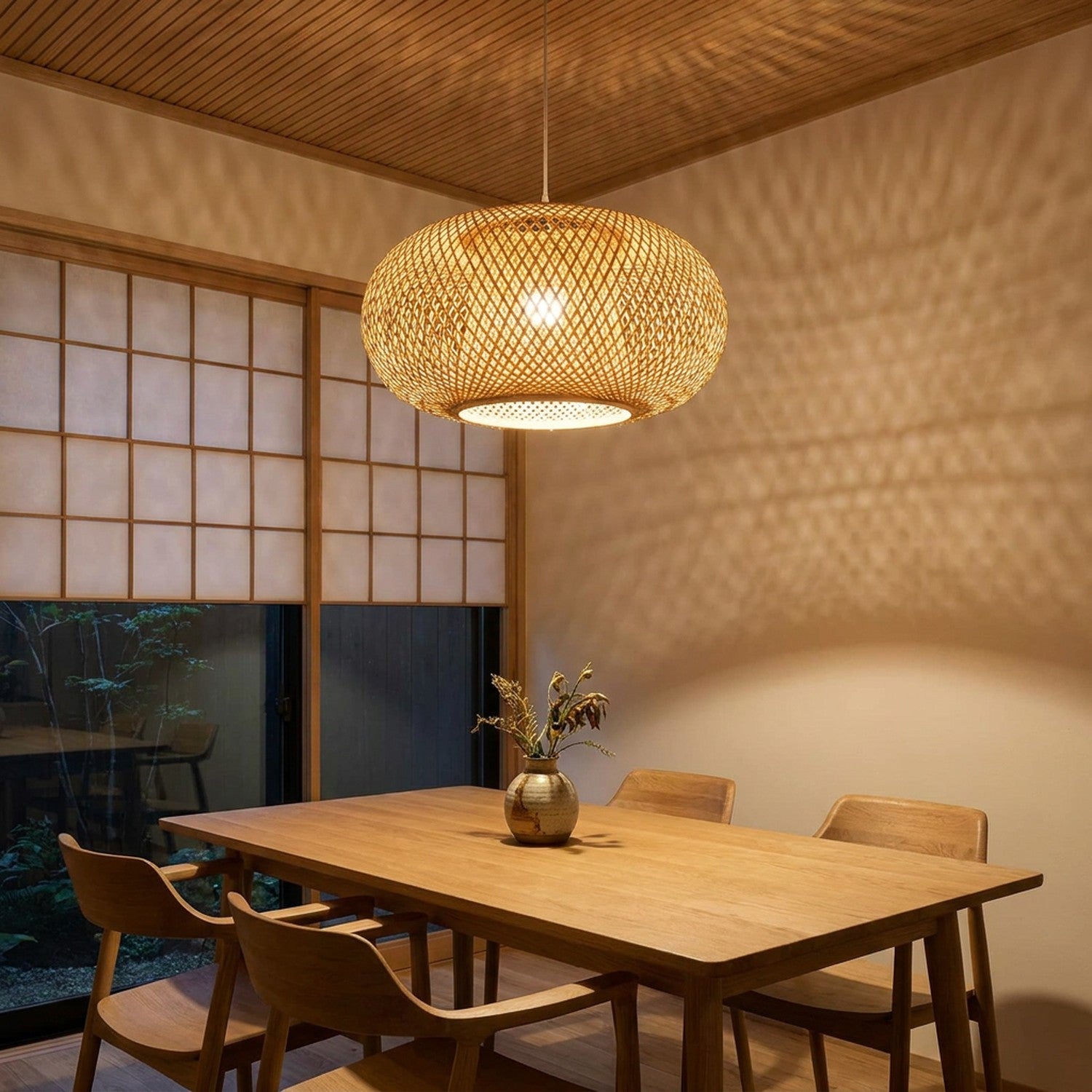 Suspension bambou tissée allumée au-dessus d'une table en bois dans une salle à manger style japandi