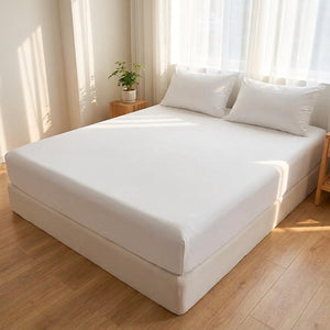 Drap housse blanc installé sur un grand lit dans une chambre lumineuse avec plante verte