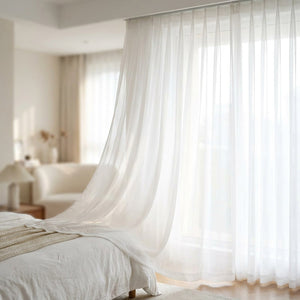 Voilage blanc plis en S suspendu à une fenêtre de chambre lumineuse