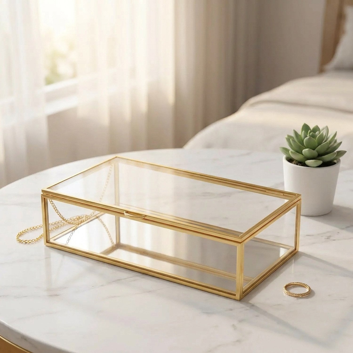 Boîte à bijoux en verre fermée sur surface marbre blanc avec petite plante grasse