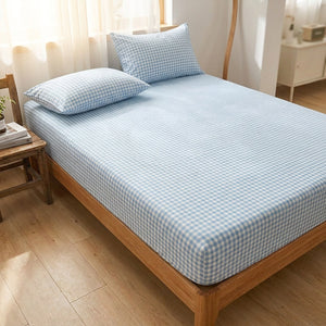 Drap housse a carreaux vichy bleu sur un lit en bois clair pres d une fenetre lumineuse