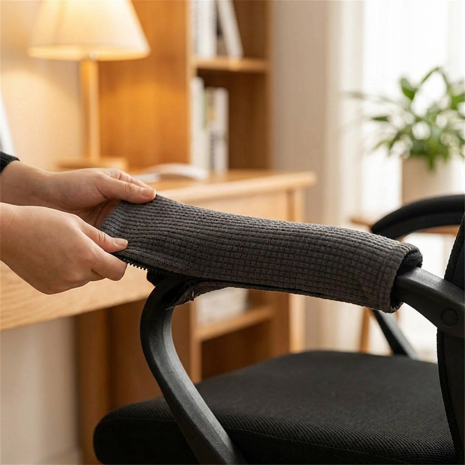 Mains installant une housse d'accoudoir grise sur un fauteuil de bureau cocooning
