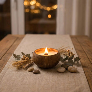Bougie coquille noix de coco allumée sur table en bois avec fleurs séchées et lin