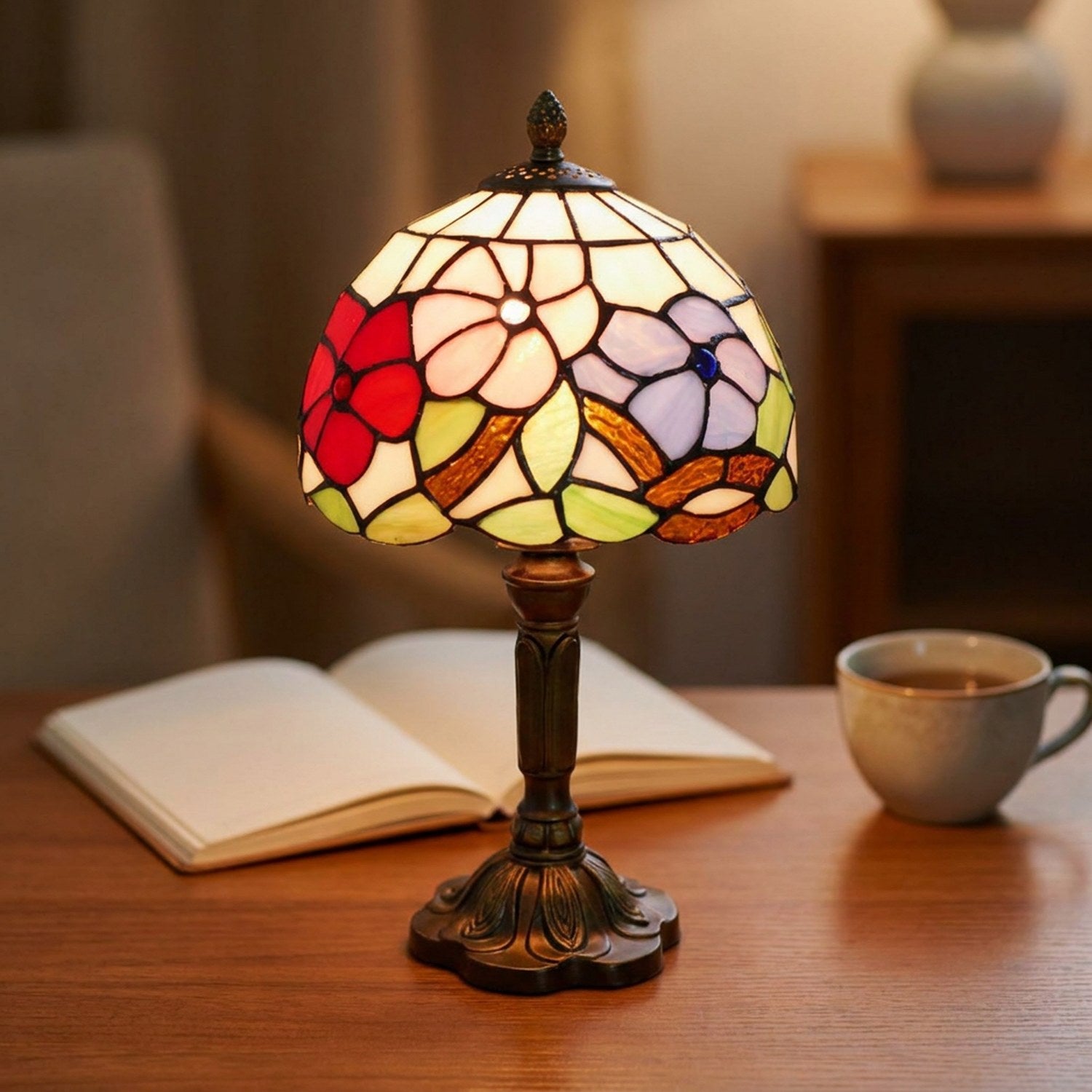Lampe style Tiffany allumée sur un bureau avec un livre ouvert et une tasse de thé