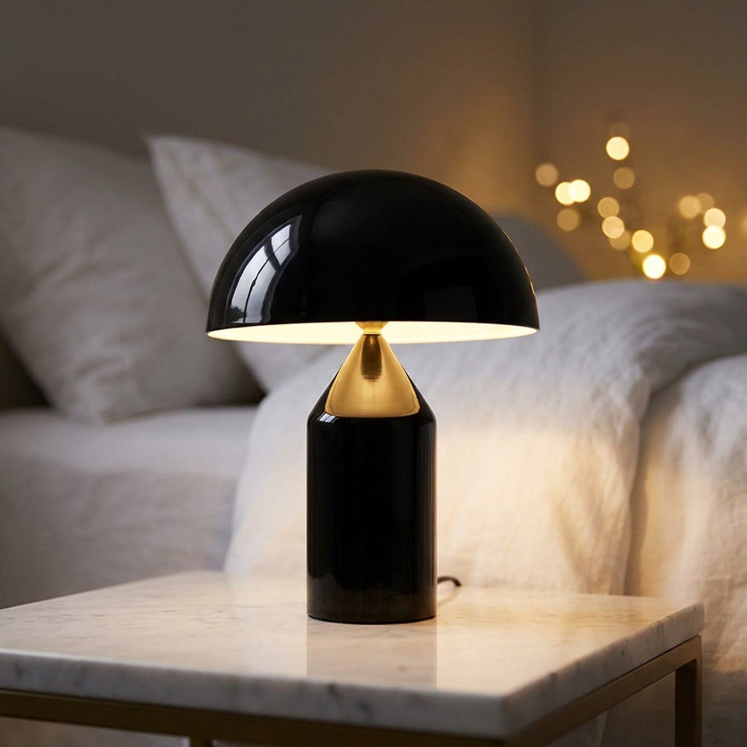 Lampe champignon noire allumée posée sur une table de chevet en marbre dans une chambre nordique cosy