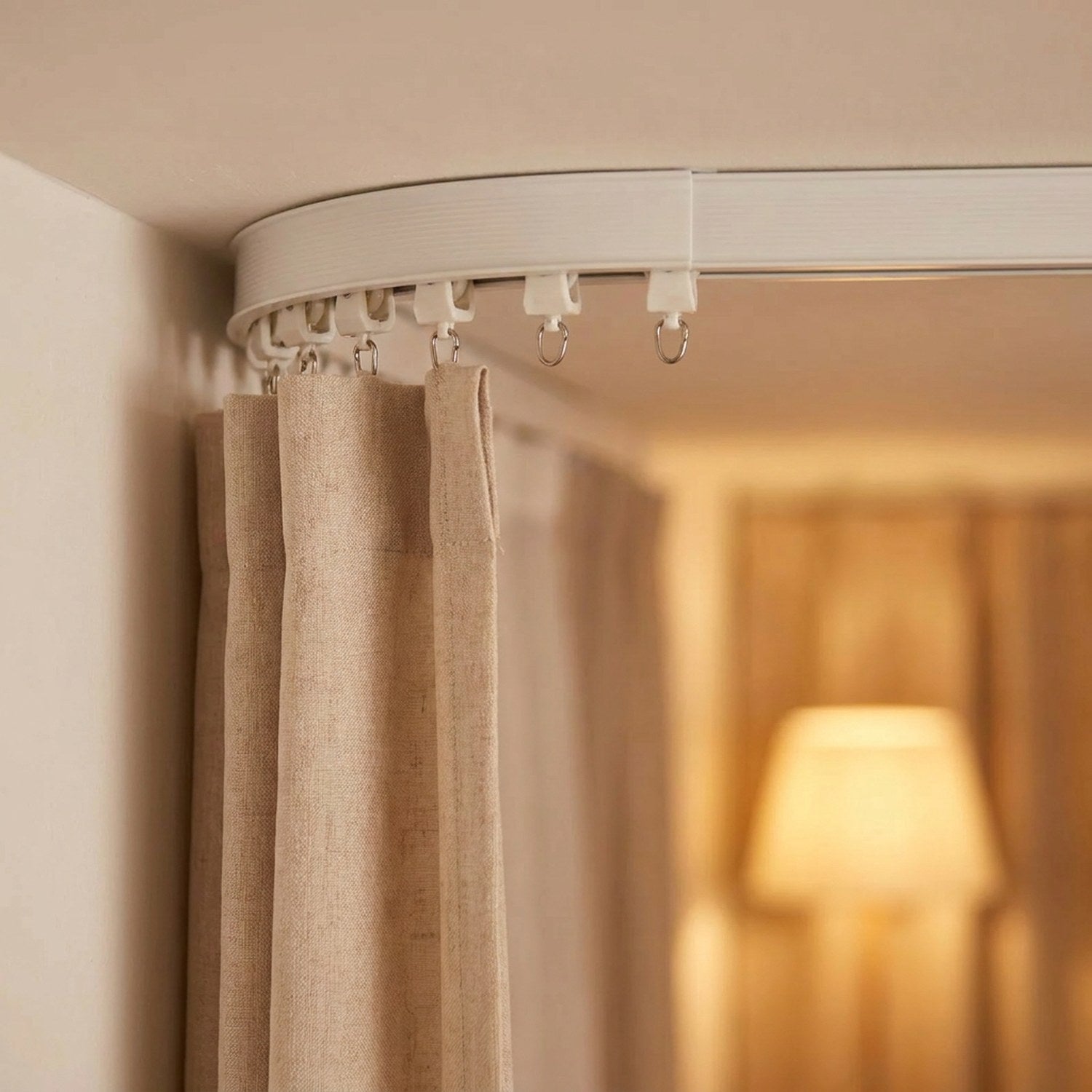 Rail de rideau plafond formant un angle avec rideau beige suspendu
