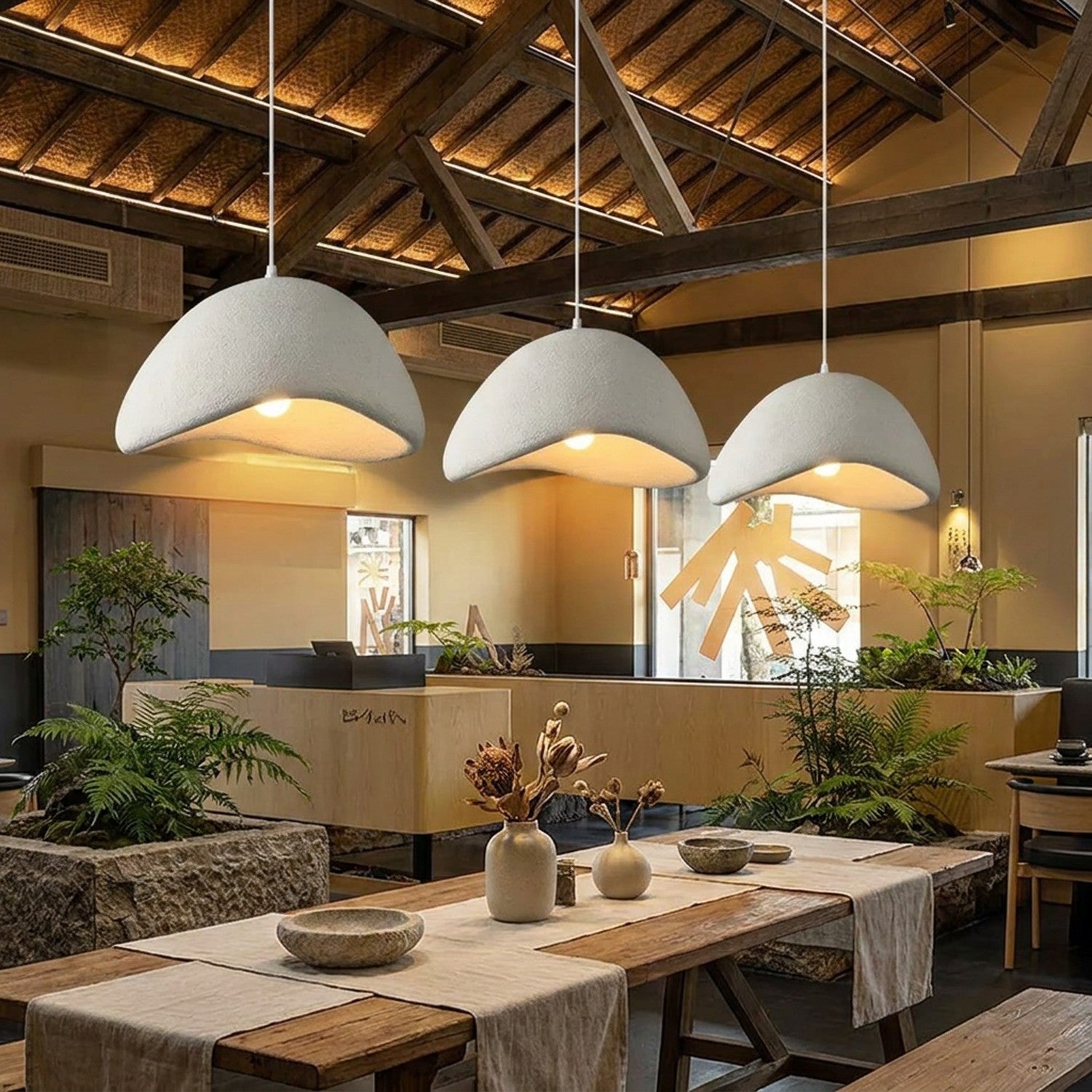 Trois suspensions Wabi Sabi blanches au-dessus d'une longue table à manger