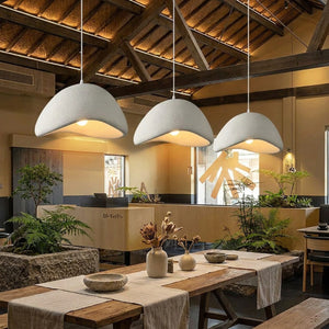 Trois suspensions Wabi Sabi blanches au-dessus d'une longue table à manger