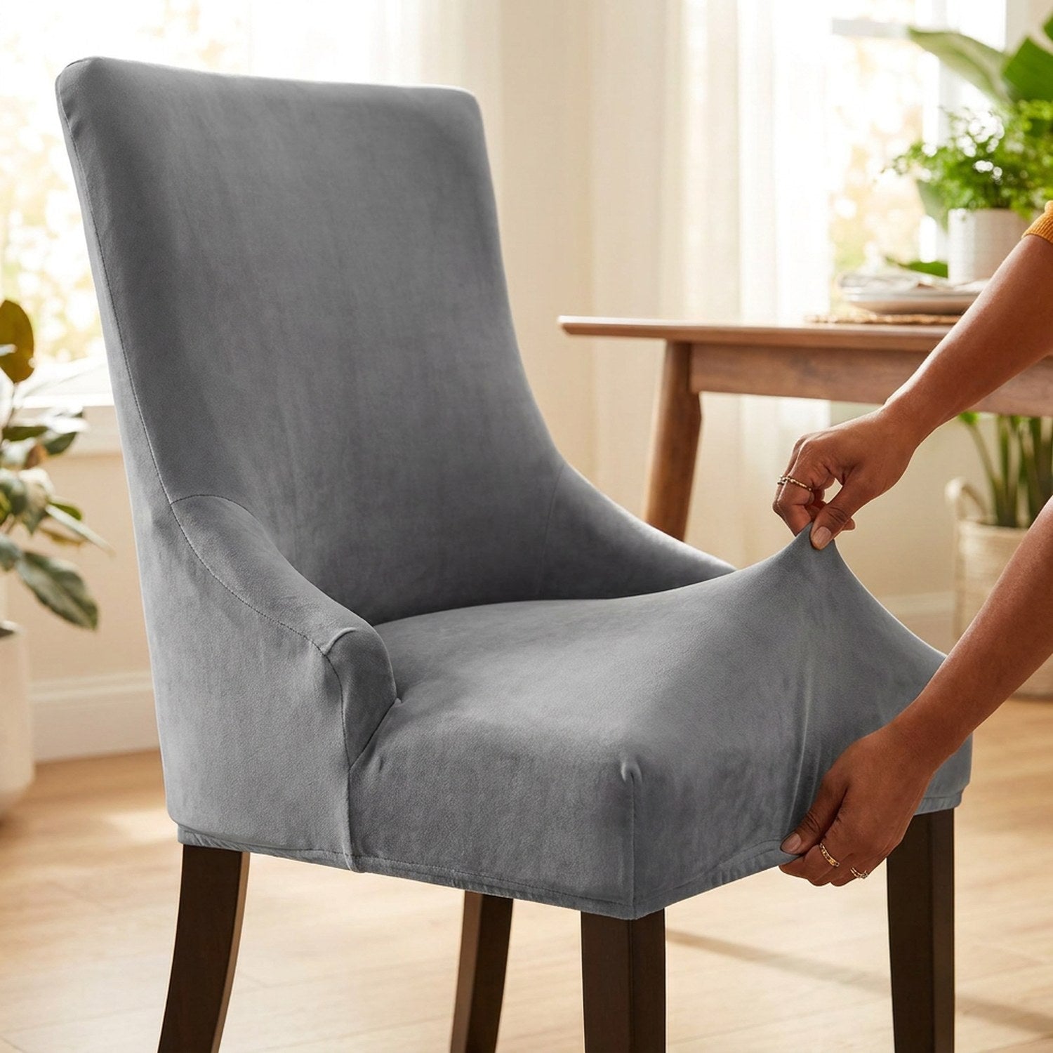 Installation de la housse de chaise extensible en velours gris sur une chaise à dossier haut