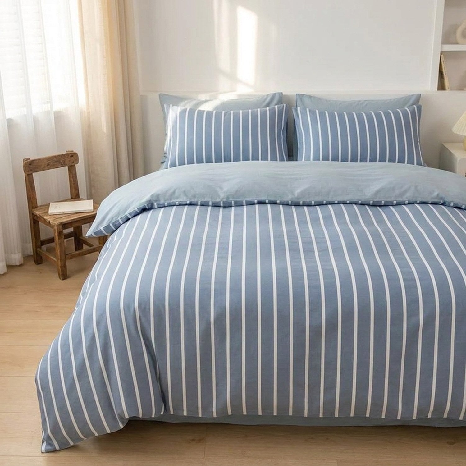 Housse de couette rayee bleue sur un lit pres d une fenetre lumineuse avec une chaise en bois