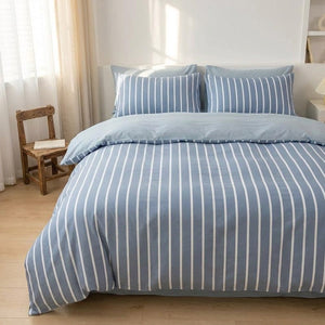 Housse de couette rayee bleue sur un lit pres d une fenetre lumineuse avec une chaise en bois