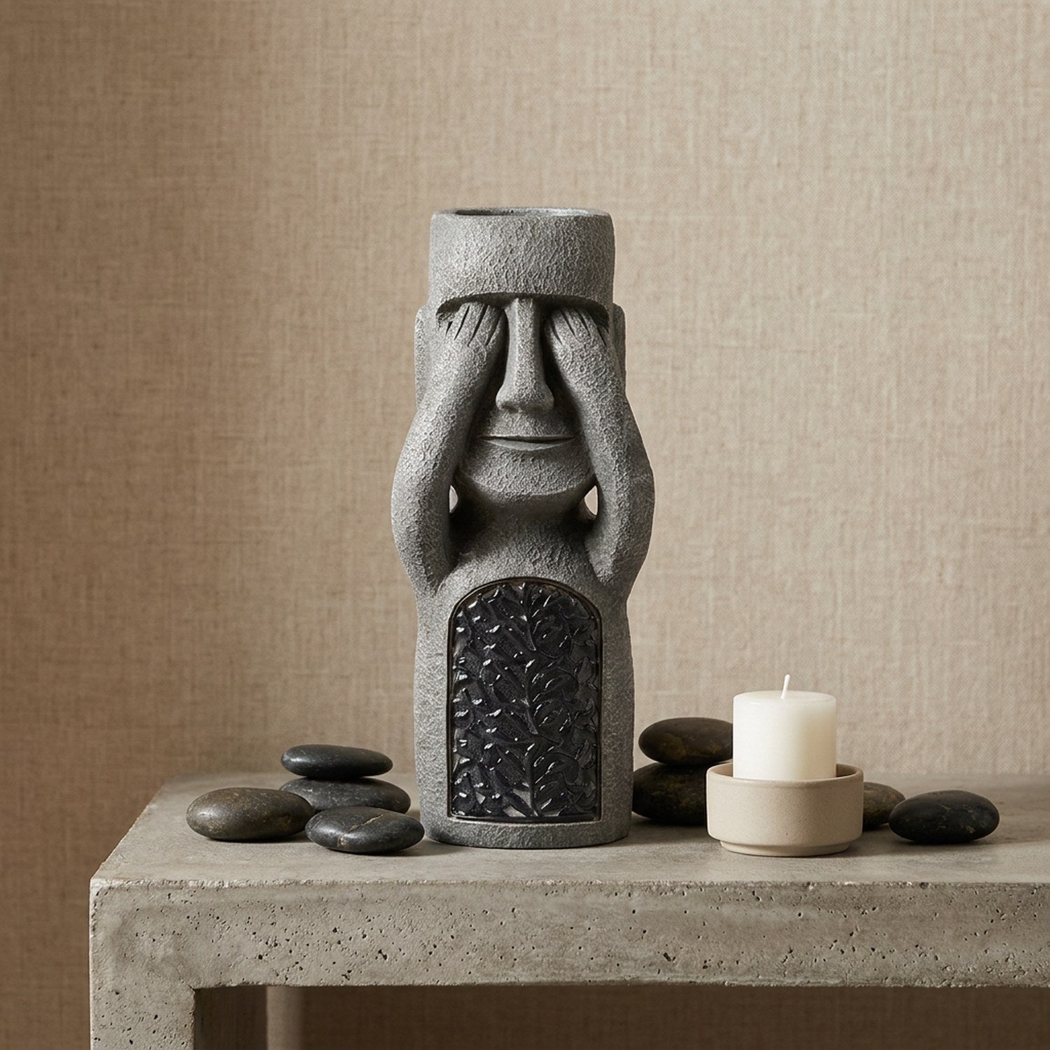 Statue Moai île de Pâques sur console en béton avec galets et bougie dans un salon élégant
