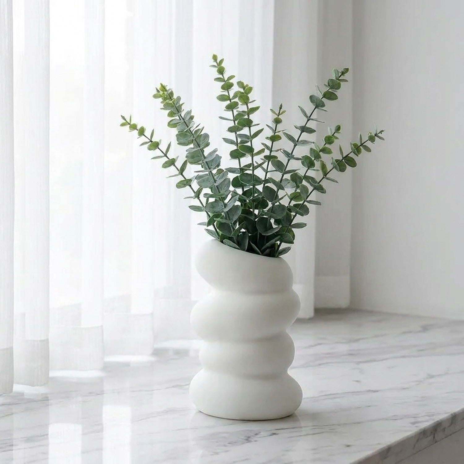 Vase bulles blanc avec eucalyptus sur marbre blanc