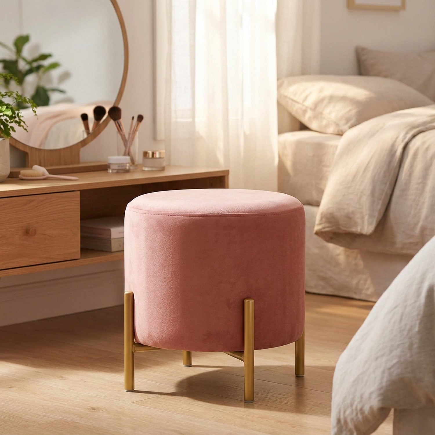 Pouf rond en velours rose devant une coiffeuse en bois avec miroir