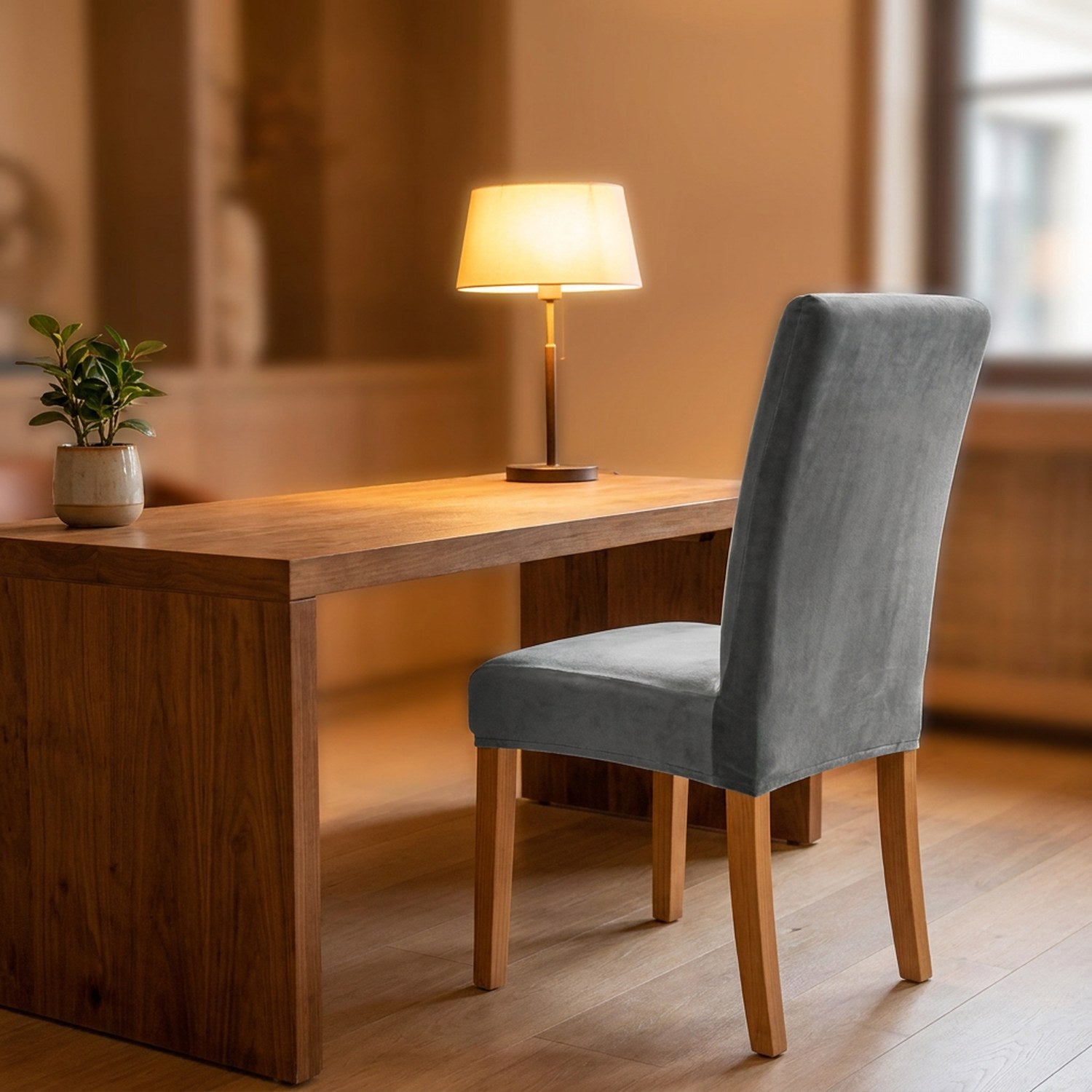 Bureau en bois avec une chaise habillée d'une housse grise en velours dans un intérieur chaleureux