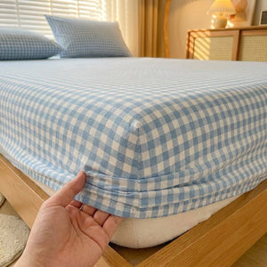 Detail du coin elastique du drap housse a carreaux vichy tire a la main sur le matelas