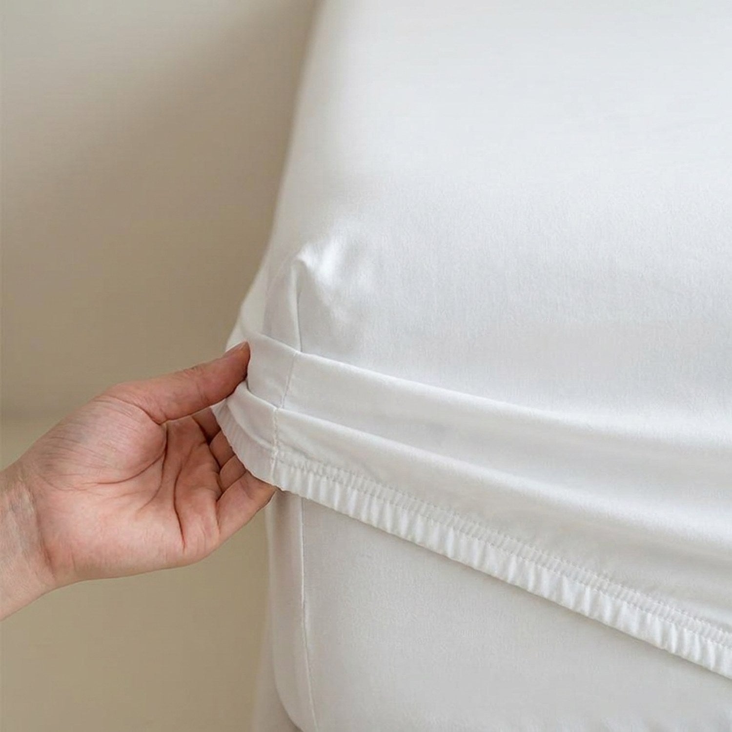 Détail de la bande élastique du drap housse tirée à la main sur le coin du matelas