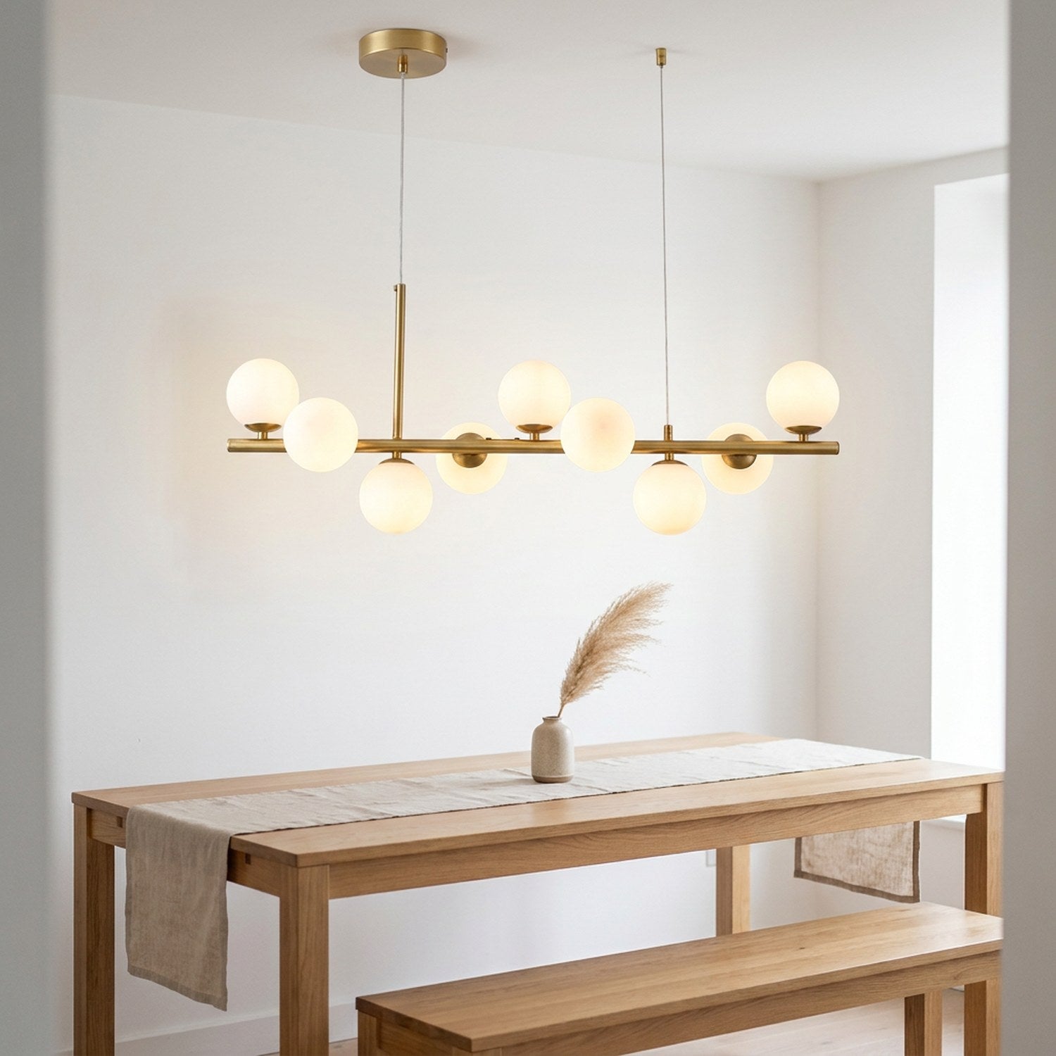 Lustre doré au dessus d'une table à manger scandinave avec banc en bois