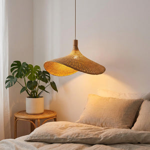 Suspension bambou corolle allumée dans un coin chambre cosy avec literie lin et plante verte